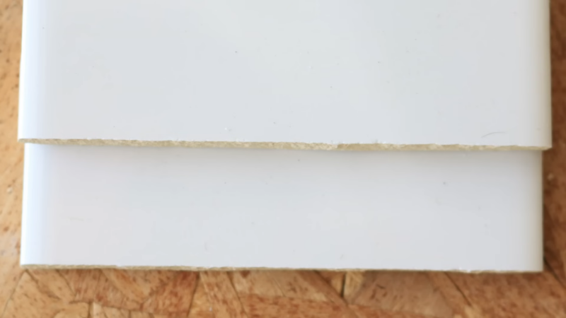 Close View of A Neatly Cut White Tile Showing Its Clean and Sharp Edge Against a Wooden Background