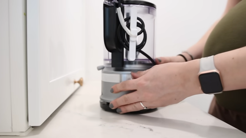 A Person Organizes a Kitchen Appliance with A Secured Cord for Storage Before Leaving for A Trip.