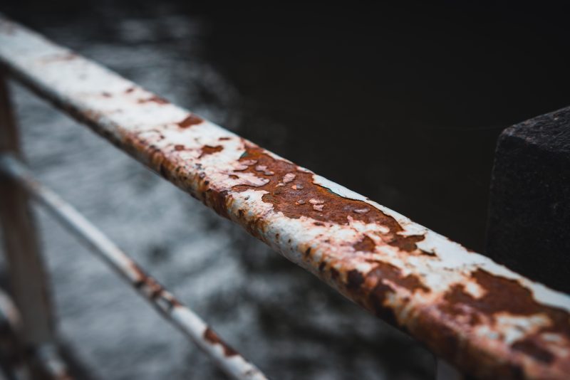 Close-up of a rusted metal railing showing corrosion and surface decay
