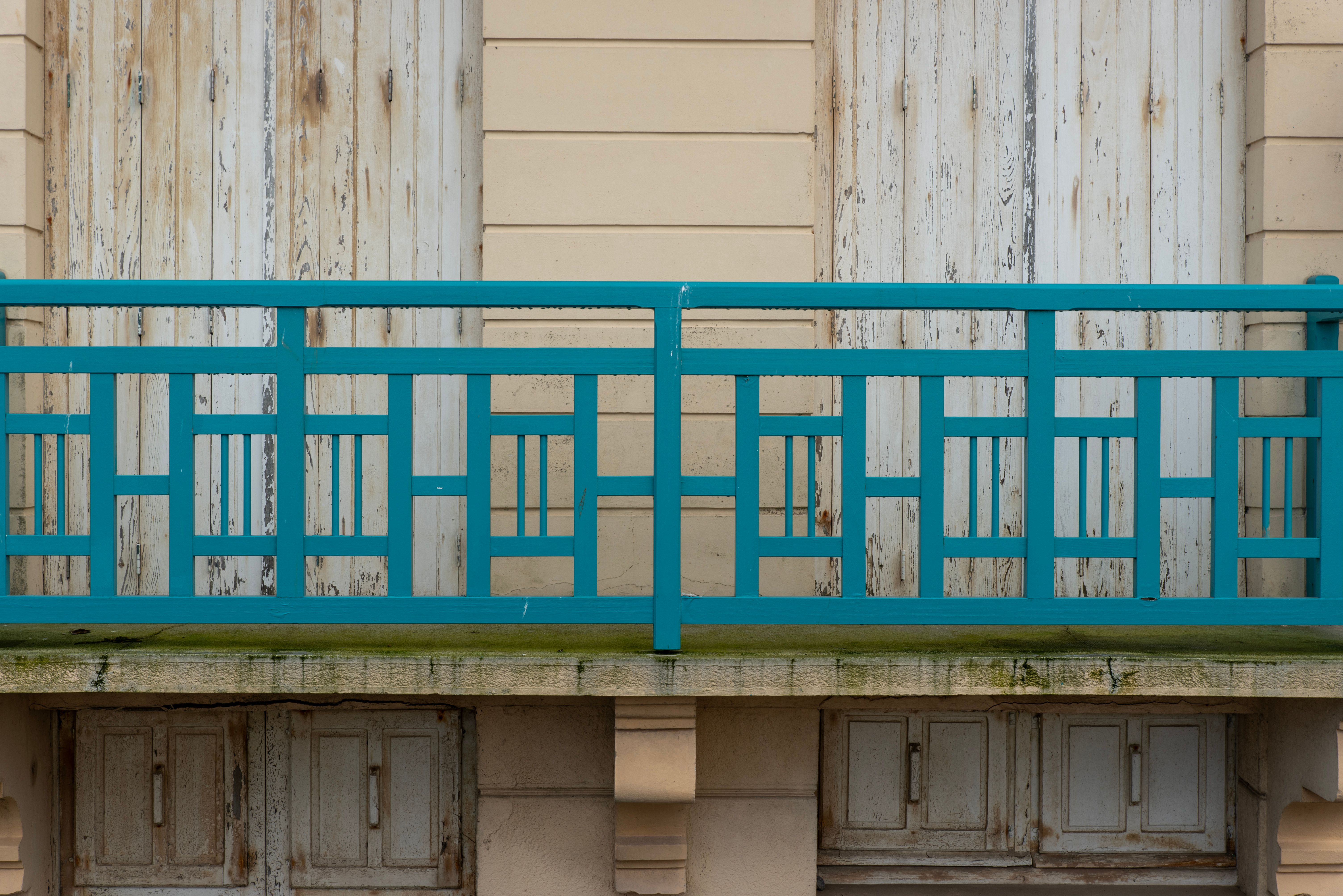 Vintage balcony with a bold blue railing and weathered wooden doors